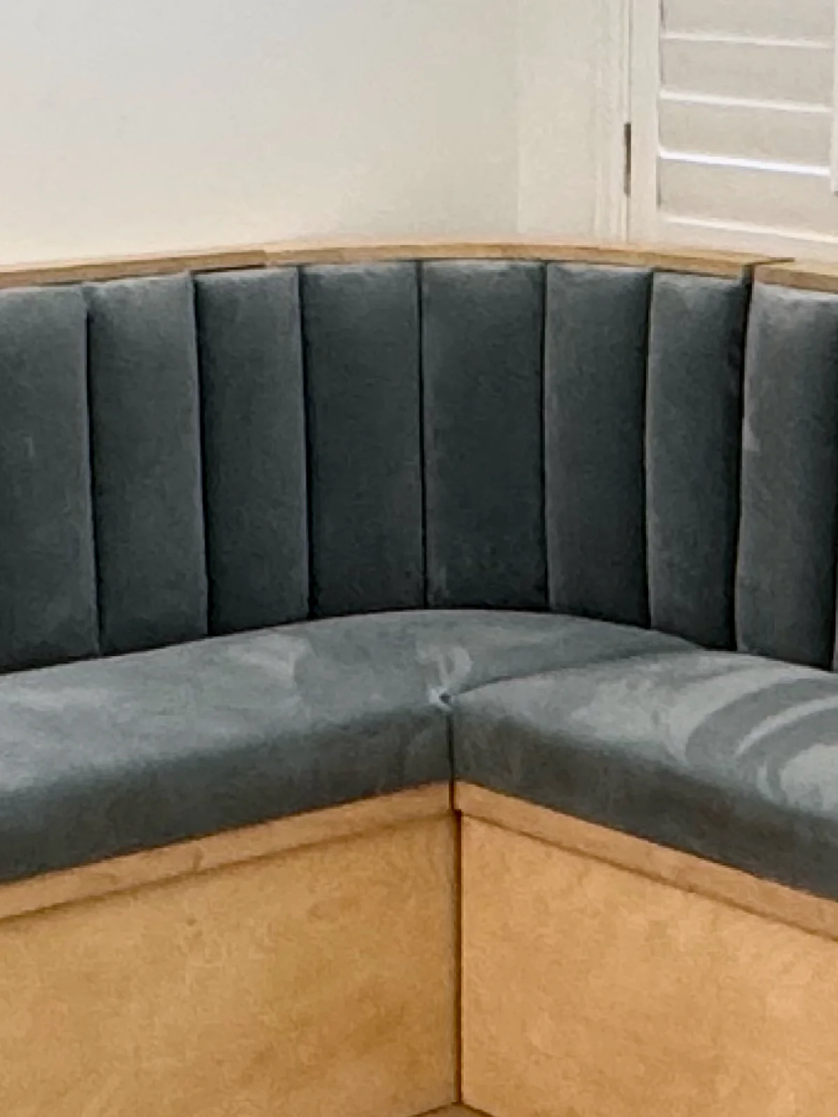 Close-up of the vertical channels on the corner banquette back, meeting at the corner above the seat and its plywood base